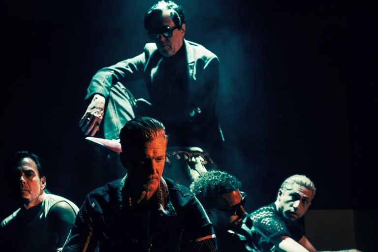 Rock band Queens of the Stone Age performing live on stage under dramatic blue and moody spotlights, featuring frontman Josh Homme.
